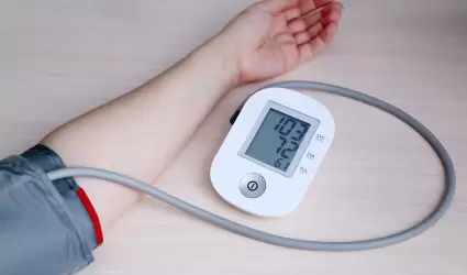 Mujer midiendo la presión arterial con autonómetro digital electrónico.