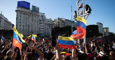 Una gran multitud ondea banderas venezolanas.