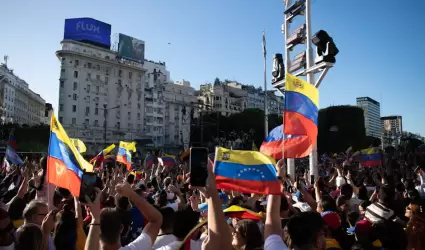 Una gran multitud ondea banderas venezolanas.